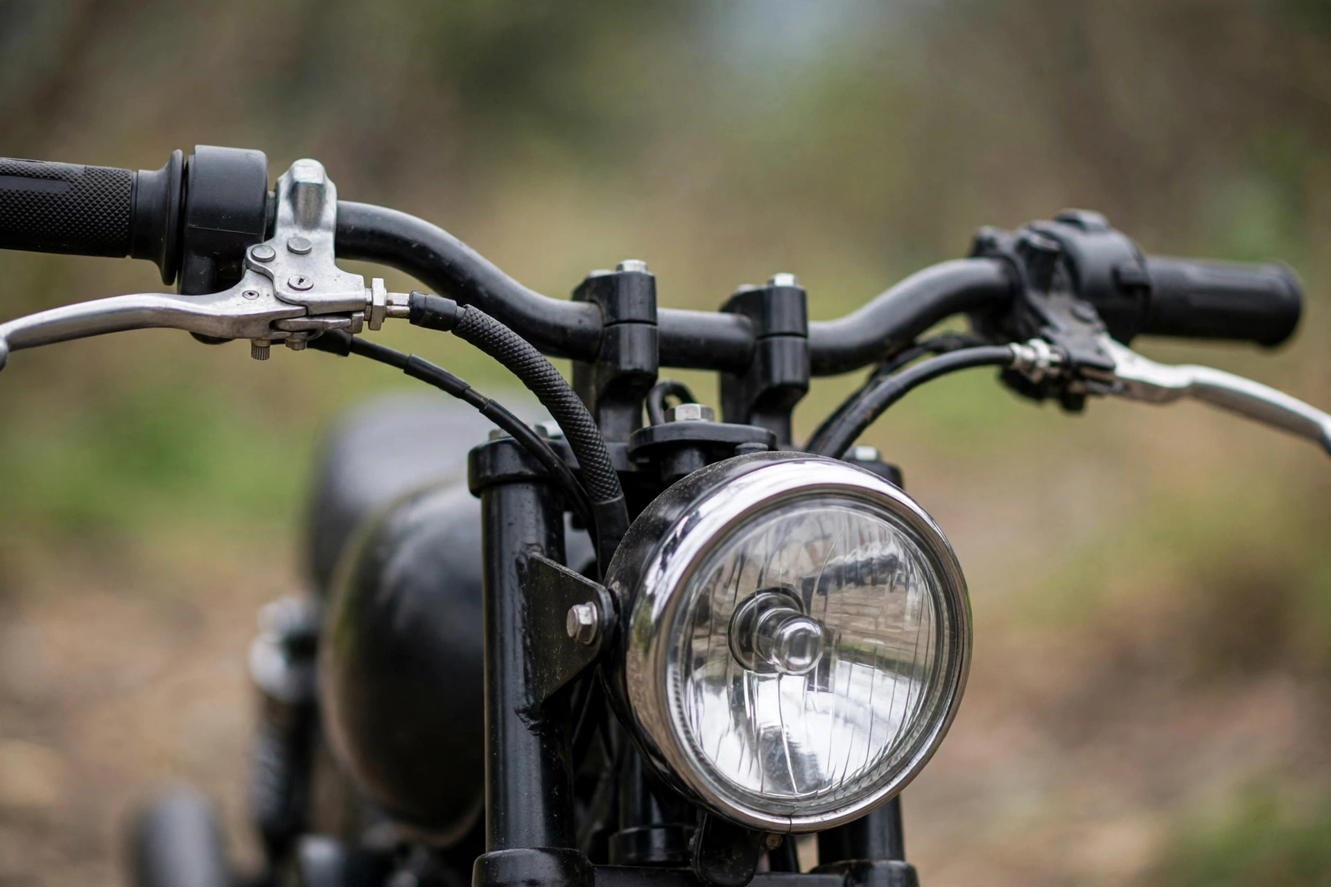 Close-up of a small motorcycle's handlebars and round headlight