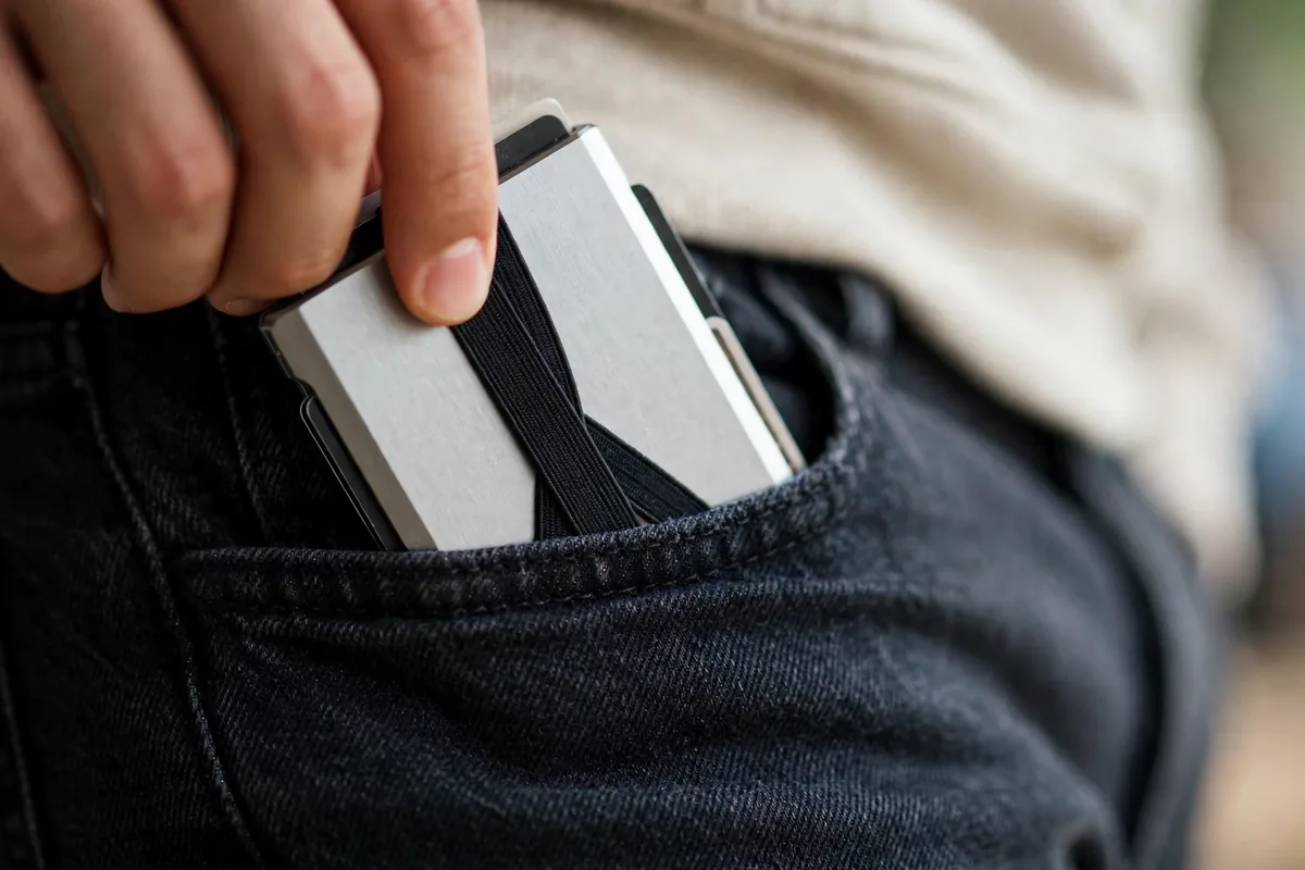 Slim minimalist travel wallet sliding into a front jeans pocket